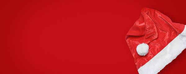 Santa Claus hat on red background. Design element, wide banner, header traditional Christmas symbol. Red velour Santa hat, top view, flat lay, copy space.