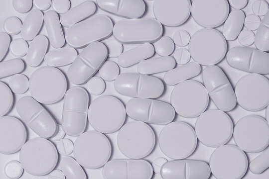 Detalle de varios comprimidos de uso medicinal sobre fondo blanco