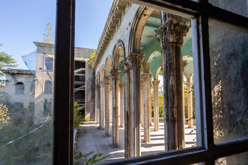 view of the colonnade through a broken window, abandoned building, former sanatorium