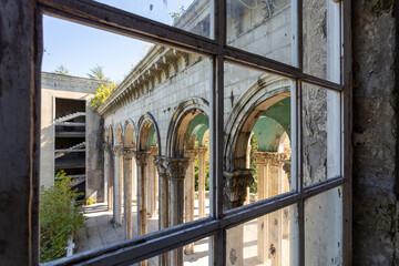view of the colonnade through a broken window, abandoned building, former sanatorium - obrazy, fototapety, plakaty