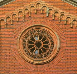 Texture front part of an ancient brick crypt with a round patterned carved window in the cemetery