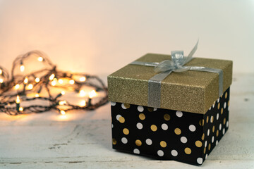 Gold and silver glitter package with a string of warm white lights on an old wooden vintage table