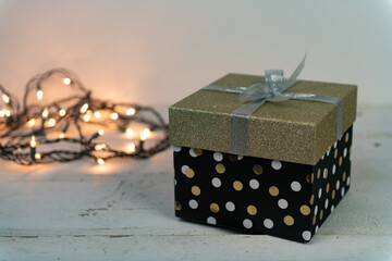 Gold and silver glitter package with a string of warm white lights on an old wooden vintage table