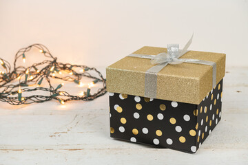 Gold and silver glitter package with a string of warm white lights on an old wooden vintage table