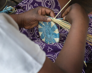 African woman hand making, weaving a basket with a pretty pattern, using grasses and natural dyes...