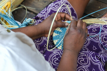 African woman hand making, weaving a basket with a pretty pattern, using grasses and natural dyes...