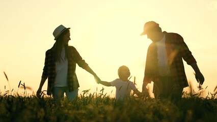 Happy family of farmers with child, are walking on wheat field. Slow motion. Mom, dad, child walk...