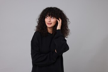 Young woman in stylish black sweater on light grey background