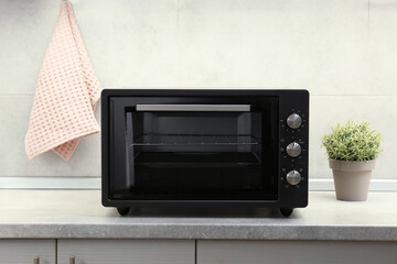 Fototapeta premium One electric oven and houseplant on grey table in kitchen