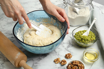 Preparing delicious pesto bread. Woman making dough at white marble table, closeup