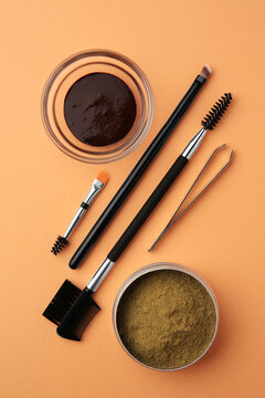 Flat lay composition with eyebrow henna and professional tools on orange background