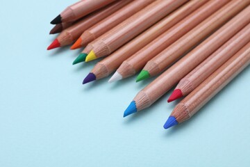 Colorful pastel pencils on light blue background, closeup with space for text. Drawing supplies