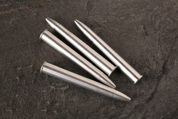 Metal bullets on dark textured table, above view