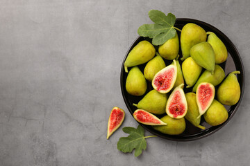 Cut and whole green figs on light gray table, flat lay. Space for text