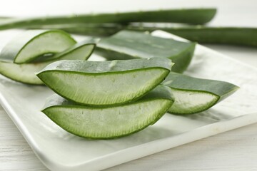 Fresh aloe vera pieces on white wooden table, closeup