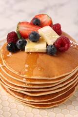 Delicious pancakes with fresh berries, butter and honey on plate, closeup
