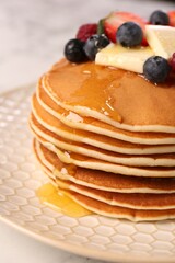 Delicious pancakes with fresh berries, butter and honey on table, closeup