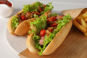 Tasty hot dogs with chili, lettuce and sauce on white table, closeup