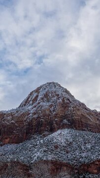 Vertical Timelapse of clouds moving over snowy cliff in Zion National Park during winter.