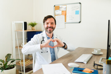 Naklejka na ściany i meble Happy doctor smiling working at the office as a cardiologist