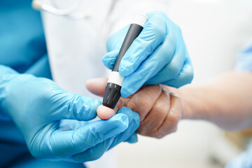 Asian doctor using lancet pen on senior patient finger for check sample blood sugar level to...