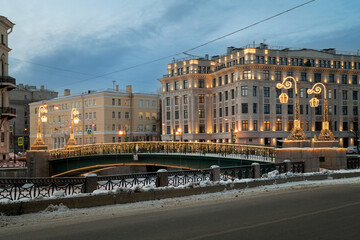 View of the Moika River embankment and Krasnoflotsky pedestrian bridge in New Year's decoration on a winter day, St. Petersburg, Russia
