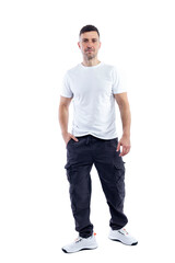 Fototapeta premium A handsome young man stands tall. A smiling brunette guy in a white T-shirt, dark trousers and sneakers. Positive and optimistic. Isolated on a white background. Vertical.