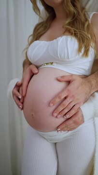 A man strokes his pregnant wife's belly