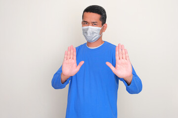 A man wearing medical mask showing stop hand sign