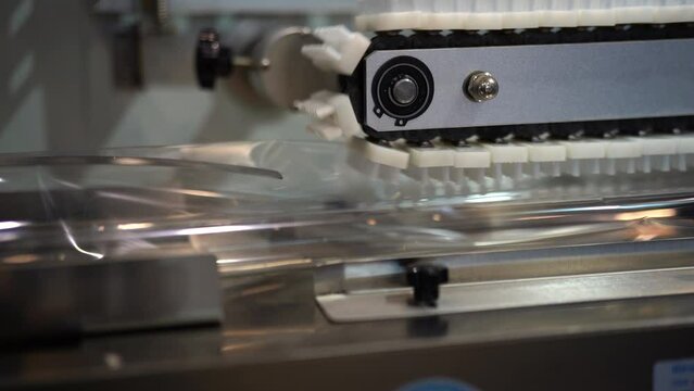 Plastic wrapping machine on production line packing food. Media. Conveyor belt with plastic boxes of cookies.