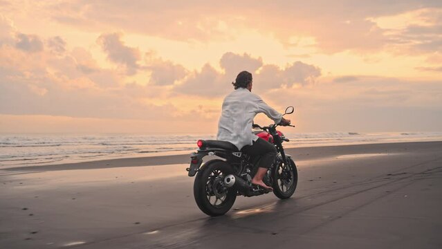 Motorbiker Riding Motorcycle or Traveling in Beautiful Nature of Beach Outdoor. Attractive Racer Man on Moto Bike with Power Motor Rides Sand in Fast Action. Freedom of Adult Person at Motorbike Trip