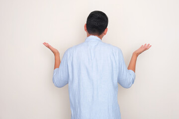 Rear view of a man showing confused gesture - obrazy, fototapety, plakaty