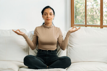 Fototapeta na wymiar Young African American woman practice crucial mindful meditation at home living room for improving mental health strength and peaceful beautiful living