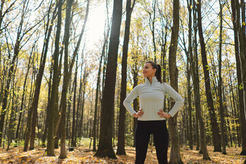 Fototapeta premium Beautiful girl doing fitness in nature on a sunny autumn forest. Body positive, sports for women, harmony, healthy lifestyle, self-love and wellness.