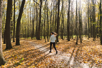 Fototapeta premium Beautiful girl doing fitness in nature on a sunny autumn forest. Body positive, sports for women, harmony, healthy lifestyle, self-love and wellness.