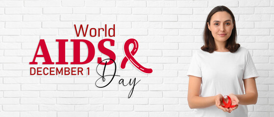 Young woman with red ribbon on white brick background. World AIDS Day - obrazy, fototapety, plakaty