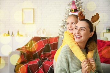 Happy mother and little daughter at home on Christmas eve