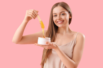 Pretty young woman with sugaring paste on pink background