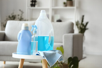 Bottles of detergent with rag on table in living room, closeup