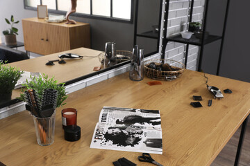 Different hairdressing tools and magazine on table in beauty salon