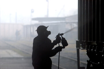 A silhouette of a worker painting a railway maintenance vehicle