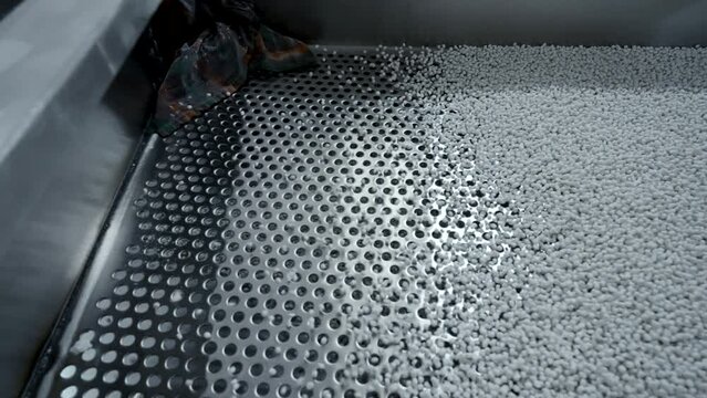 Cleaning of polymer granules. Creative. Mesh for cleaning white polymer granules from debris and foreign particles. Chemical workshop for plastic processing and cleaning