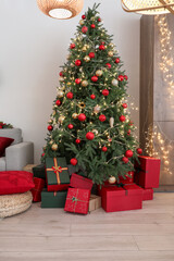 Fototapeta na wymiar Christmas tree with glowing lights, gift boxes, red and golden balls in living room