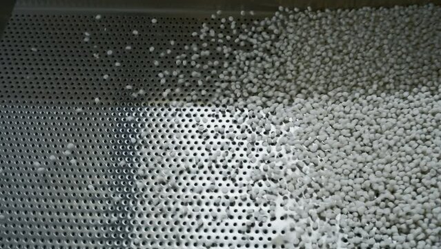 Cleaning of polymer granules. Creative. Mesh for cleaning white polymer granules from debris and foreign particles. Chemical workshop for plastic processing and cleaning