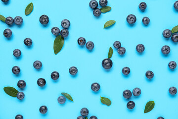 Many fresh blueberries and leaves on blue background