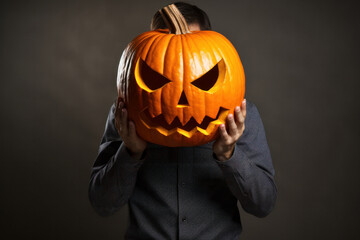 Mysterious man in leather jacket, pumpkin head for Halloween. Eerie smile, dark background. Spooky party look. AI Generative marvel.