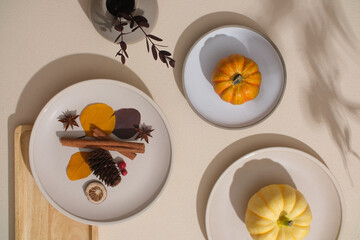 Overhead view of an Autumnal place setting with pumpkins, autumn leaves, herbs and a decorative ceramic dish. Copy space for ads and more.
