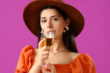 Young woman drinking wine on purple background, closeup