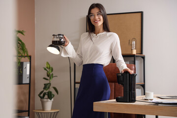 Young businesswoman with coffee machine pot in office