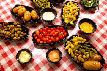 Olives with pits, cherry tomatoes, pickled peppers and cucumbers with various sauces are an appetizer before main course on the table. Lebanese cuisine